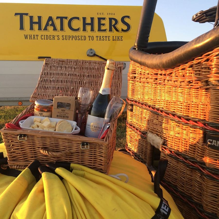 A hamper of local cheese and sparkling cider beside the basket